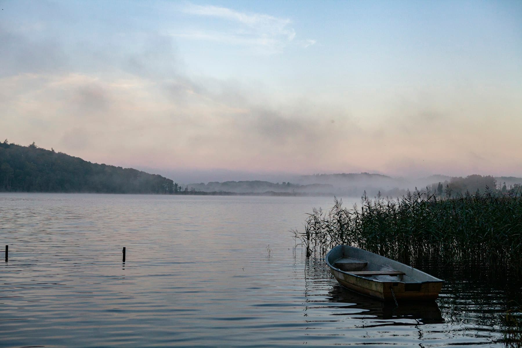 A wooden boat at rest on the lake in the early morning haze