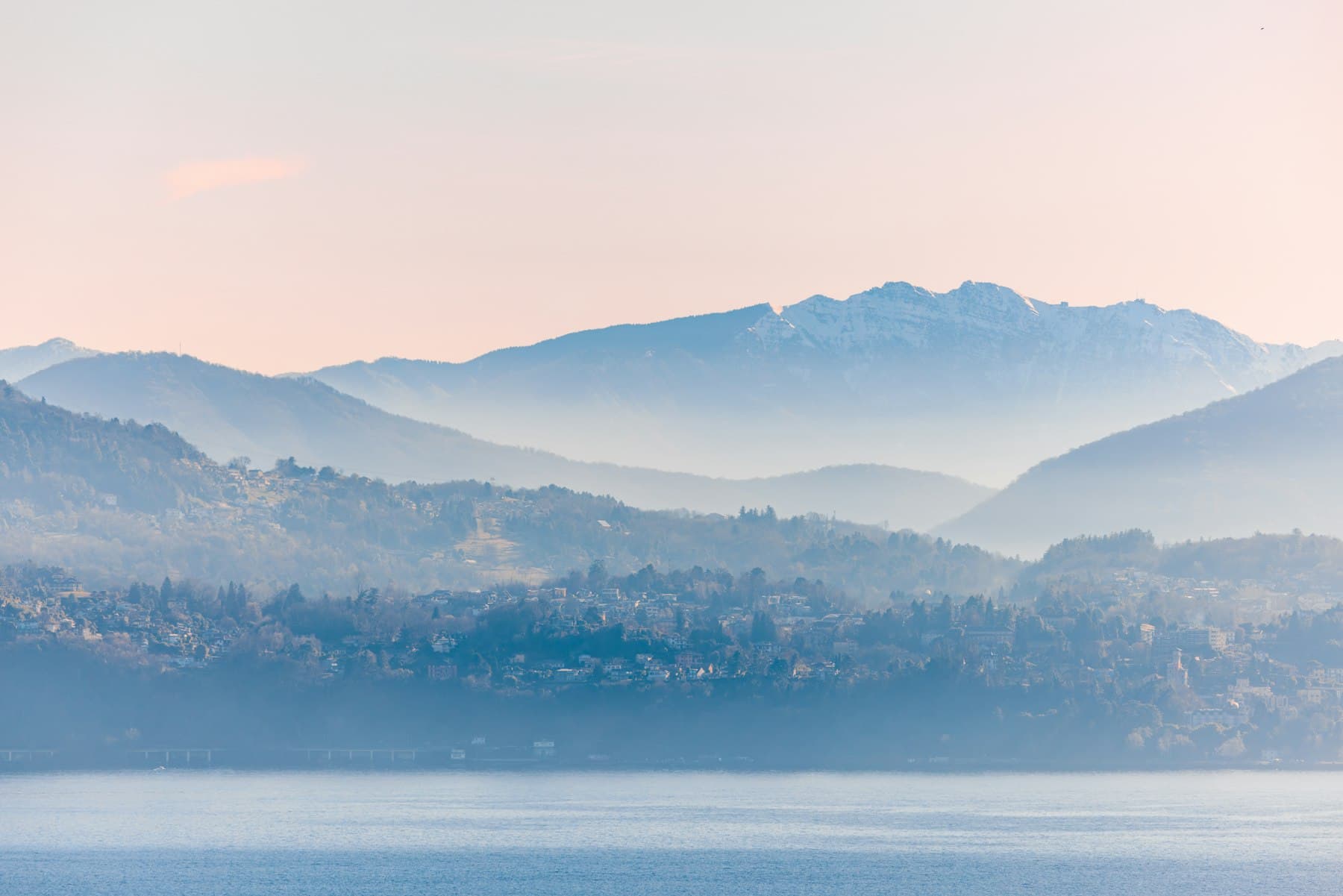 The lake in the morning haze, with mountains behind it